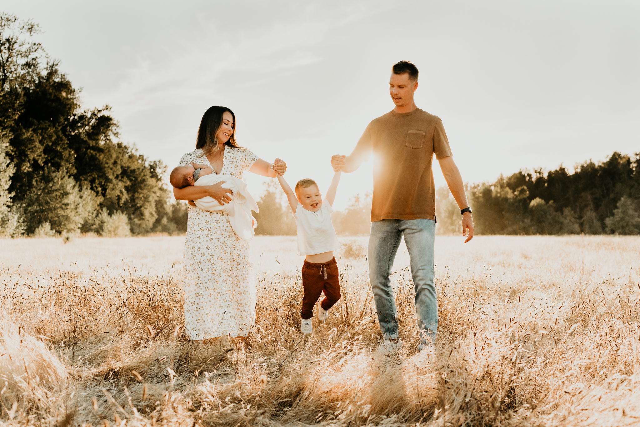 family of four swinging little boy in the sun
